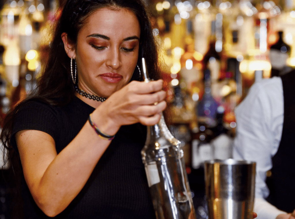 ragazza che impugna una bottiglia dietro al banco bar