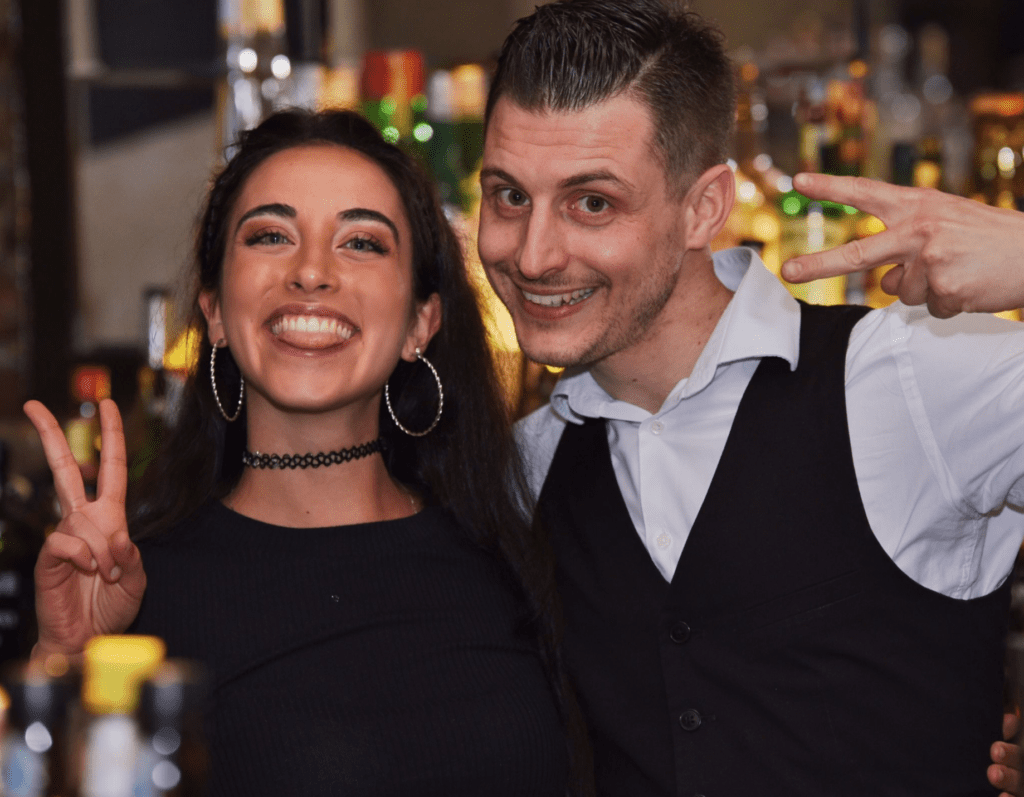 ragazza che sorride di fianco a un barman